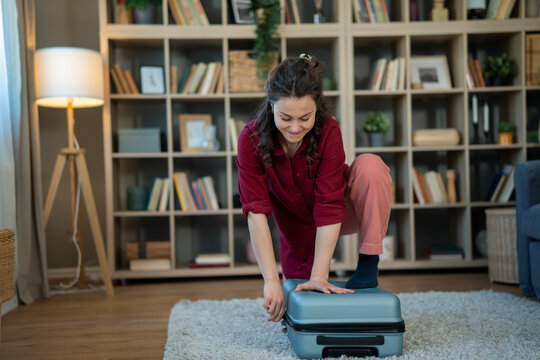 Woman packing overfilled suitcase preparing for travel