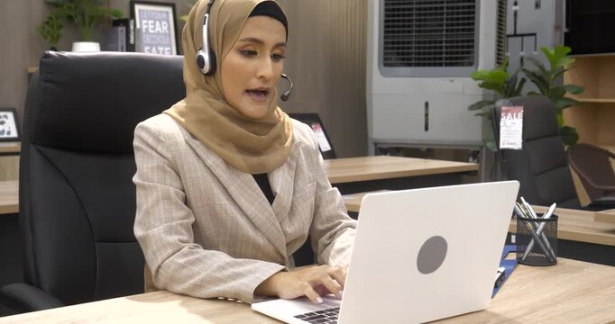 Muslim Women helpdesk call center use headphones talk to customer. Asian woman operator assistant customer service agent. Muslim Islam Businesswoman use laptop computer video call online meeting