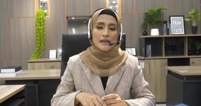 Muslim Women helpdesk call center use headphones talk to customer. Asian woman operator assistant customer service agent. Muslim Islam Businesswoman use laptop computer video call online meeting