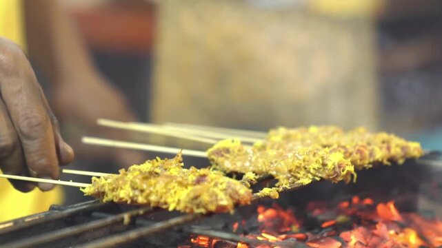 Sate klatak grilling over hot charcoal, smoky Indonesian lamb satay skewers with fire flare in a dramatic street food close-up.