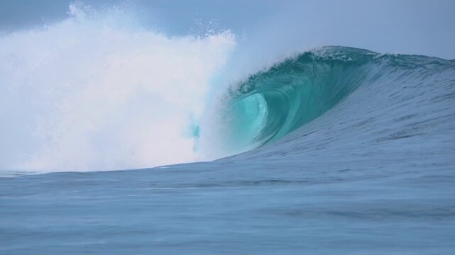 SLOW MOTION: Perfect blue barrel peels across a tropical reef with smooth walls and crisp hollow opening. Offshore mist and reflective water emphasize the beauty of empty wave in the Mentawai Islands.