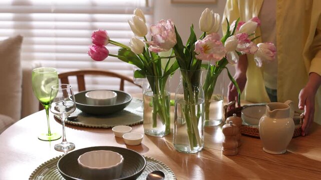 Woman setting table for dinner in dining room, closeup. Camera moving forward
