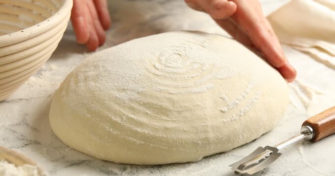 Woman scoring sourdough with lame at table, closeup