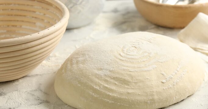 Sourdough, proofing basket and lame on white table, closeup. Camera moving right