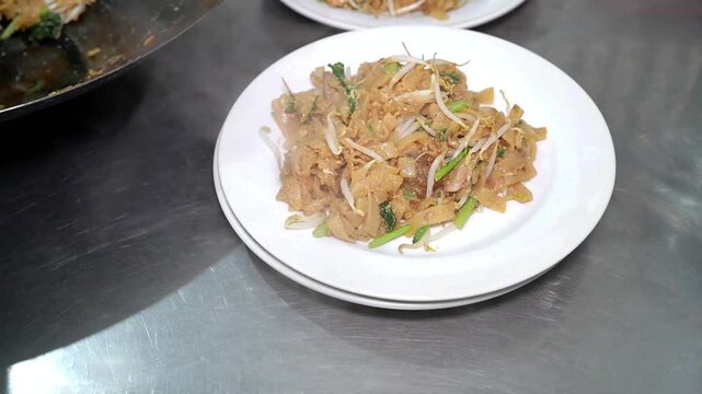 Beef fried rice noodles served fresh from the wok, a savory Asian street food with flat rice noodles, bean sprouts, and green vegetables.