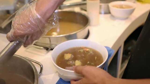 Indonesian beef bone meatball soup with rich hot broth, a comforting street food dish freshly served in a kitchen.
