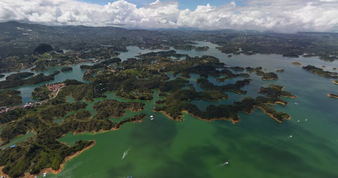 Aerial view of El Penon de Guatape overlooking the vast reservoir with lush green islands and boats under a cloudy sky Guatape, Antioquia, Colombia.