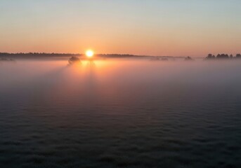 Obraz premium Beautiful Sunrise Over a Misty Lake with Golden Light Piercing Through Fog; Concept for New Beginnings, Tranquility, Peace, Nature Beauty, and Morning Serenity.