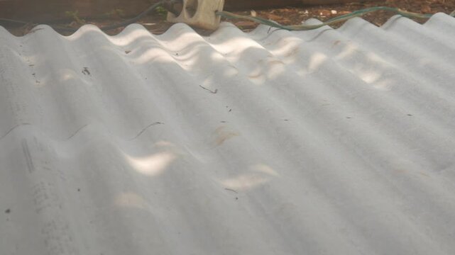 A construction worker uses a hand grinder to cut asbestos or fiber cement roofing sheets.