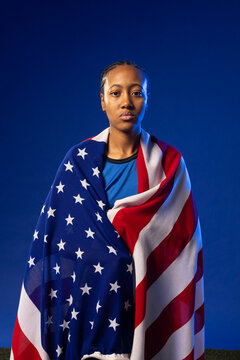 African American woman standing in studio, wearing blue athletic top and American flag