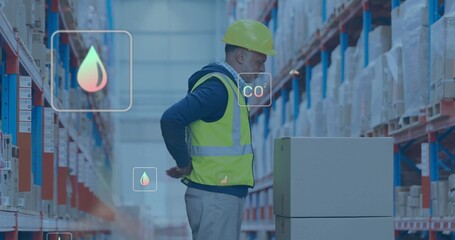 Worker wearing yellow hardhat neon vest checking boxes on pallet in warehouse aisle, CO2 droplet © vectorfusionart