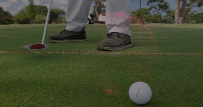 Lining up golfer in light-trousers dark-golf-shoes on green, with golf ball, putter, red-rim cup