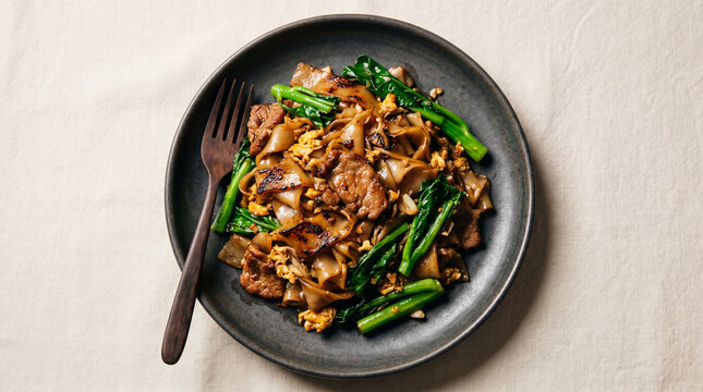 A top-down shot of a flavorful pad see ew dish, a culinary delight ready to be savored. This image offers a glimpse into the art of food presentation, showcasing textures, colors.