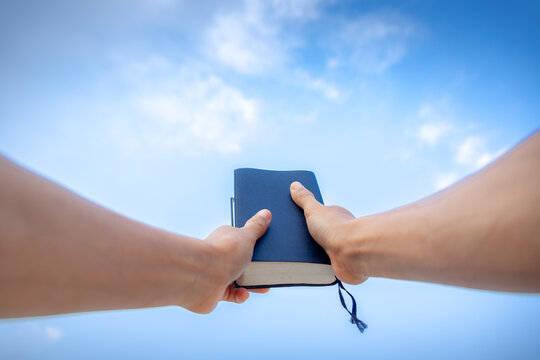 hand holding Bible, with the sky as the background in morning. copy space.