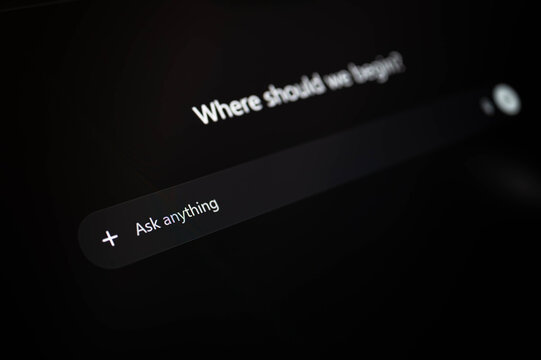 Abstract blurred close up of AI chatbot interface with prompt input field and text on dark screen, representing artificial intelligence, user query, and modern technology concept