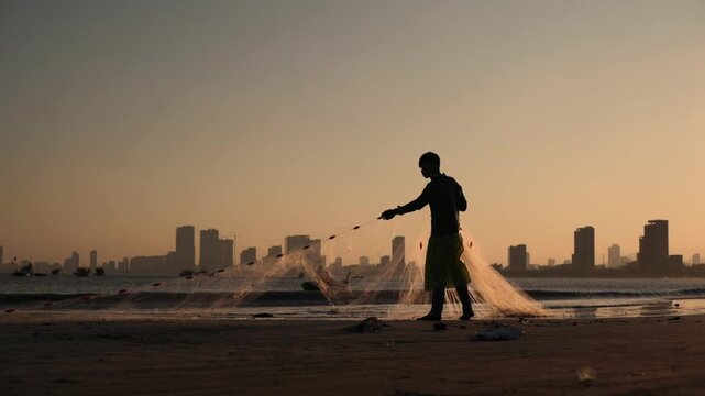 Morning Fishing Scene. Angler At Dawn Casts Fishing Net. Sunrise Over City As Fisherman Prepares To Fish. Early Morning Scene With Fisherman And Urban Skyline In Background