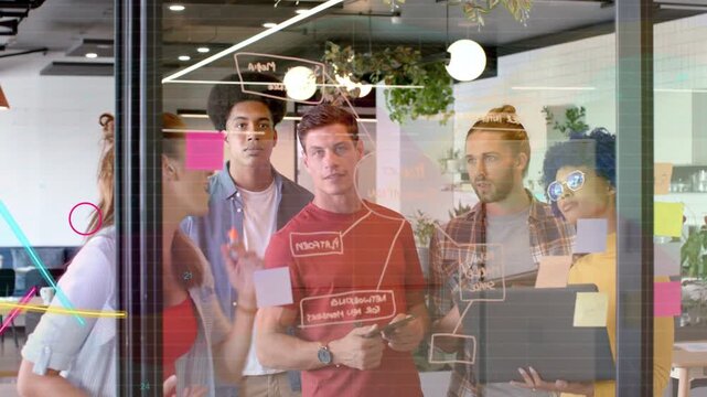 Team lead placing sticky notes drawing plan on glass for business laptop overlaying waves on glass