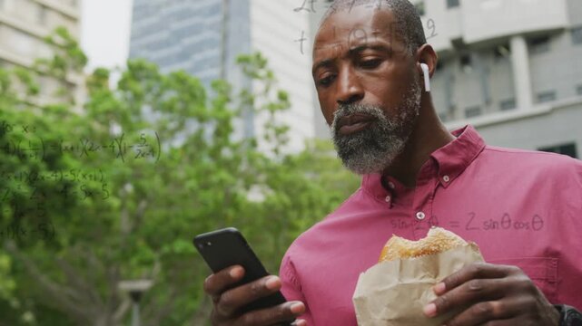 Mature man standing park, scrolling phone and eating, causing math graphs building up for education