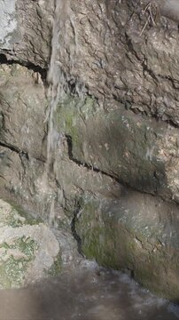 Dilapidated water drainage. Cracked wall with algae growth. Moss and grime signal drainage issues. Environmental neglect causes decay and environmental deterioration visible
