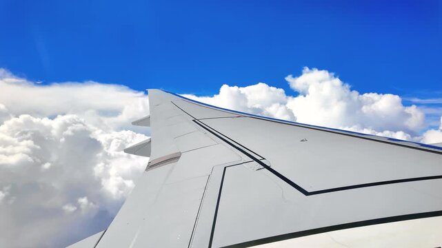 Commercial aircraft wing soaring above white cumulus clouds, copy space