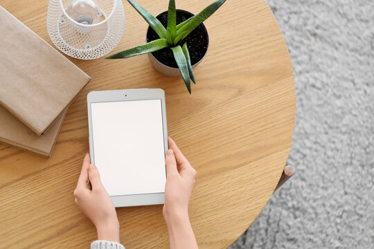 Female hands with blank tablet computer on table at home, top view