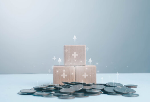 Healthcare investment concept with wooden blocks and medical cross icons on coins, financial growth, insurance, savings, medical funding and economic planning for health services.