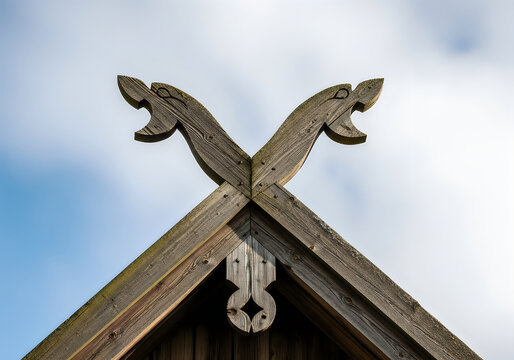 Traditional wooden roof gable with ornate carved dragon head decorations against a bright sky