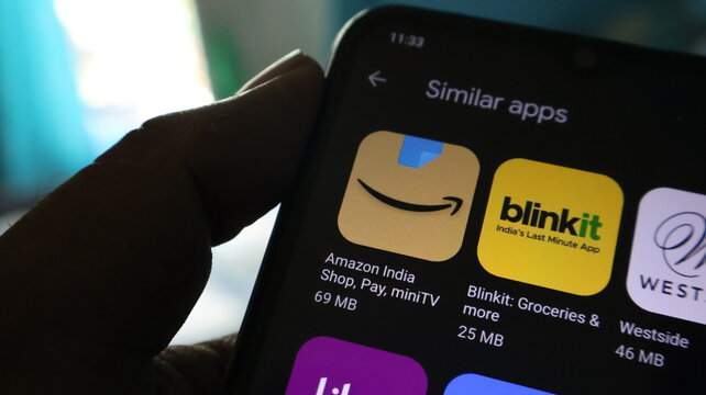 A hand holding a smartphone displaying similar apps on the screen