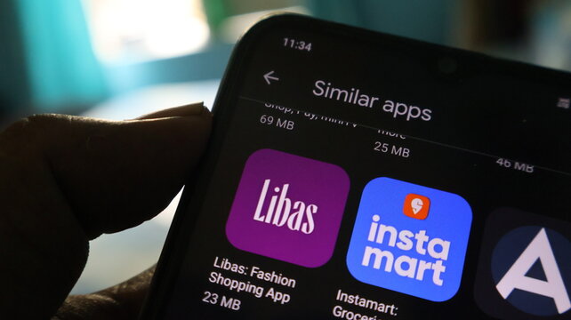 A person holding a smartphone with shopping apps on the screen