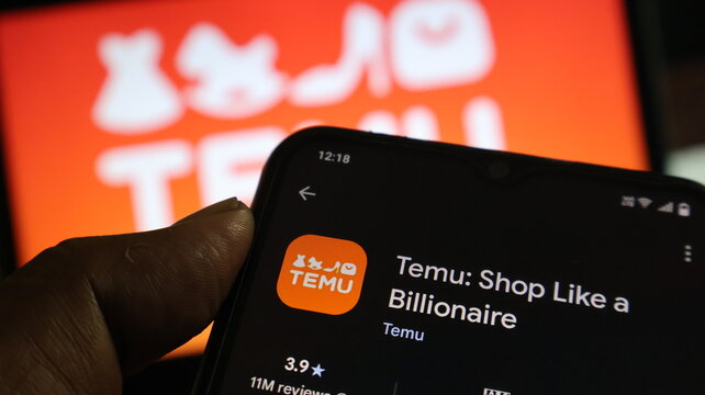 A hand holding a smartphone with the Temu app on the screen