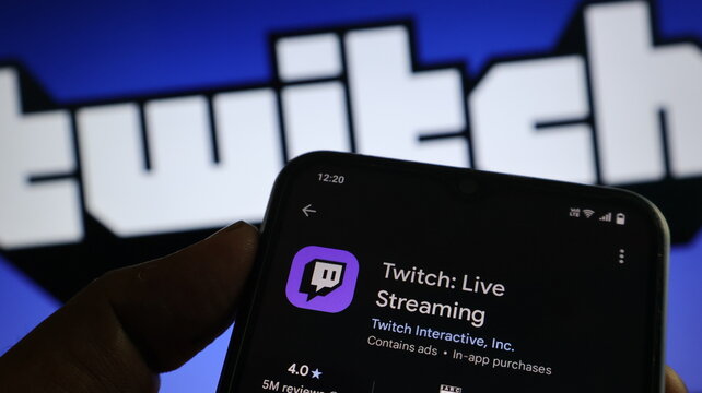 A hand holding a smartphone with the Twitch app open on the screen