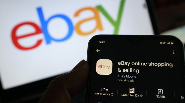 A hand holding a smartphone with the eBay app open on the screen