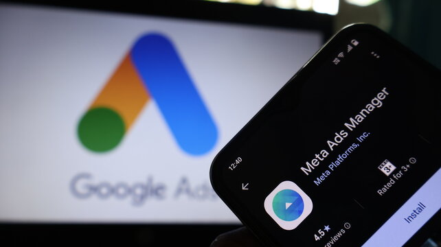 A smartphone displaying the Meta Ads Manager app in front of a Google Ads screen