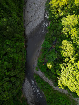 Aerial view of Mount Leuser National Park featuring a winding river flowing through dense tropical rainforest with rocky banks in Kecamatan Darul Hasanah, Aceh, Indonesia.