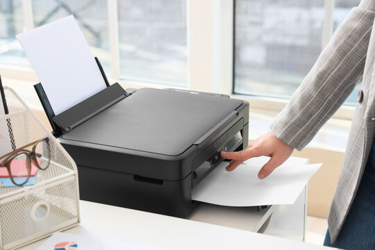Businesswoman using modern printer in office