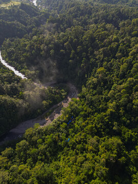 Aerial view of Mount Leuser National Park with a winding river flowing through dense tropical rainforest and lush green canopy Kecamatan Darul Hasanah, Aceh, Indonesia.