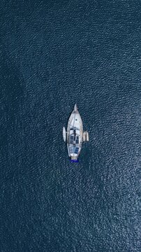 Aerial view of a sailboat with solar panels on deck anchored in the deep blue waters of the sea near We Island Sabang City, Aceh, Indonesia.