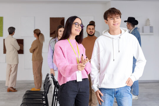 Female guide with young man at exhibition in art gallery