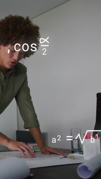 Vertical video: Engineer aligning plans at desk designing, metal disk passing causing math showing