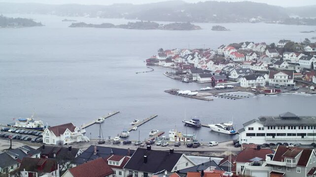 Panoramic view of &Oslash;ya Island off the coast of Krager&oslash; in southeastern Norway on a cloudy day, with Nordic wooden architecture, exclusive homes, and residential areas featuring several yacht docks