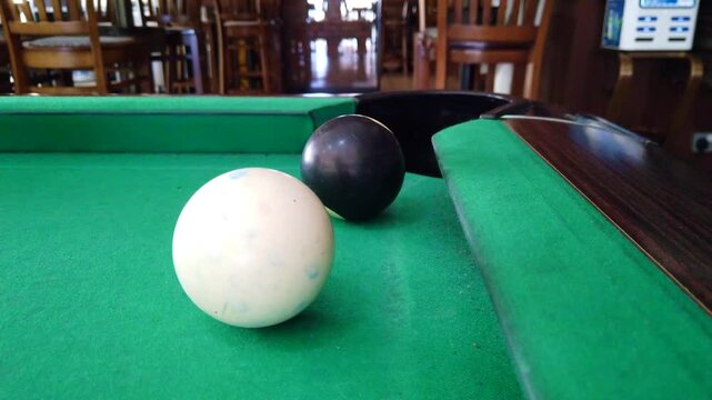 Close-up footage of the final black ball being potted in a pool game on a billiards table. The shot captures the decisive moment of gameplay, making it ideal for themes such as competition, nightlife,