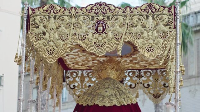 Ornate golden embroidery and red velvet adorning a religious float, part of a traditional Holy Week procession