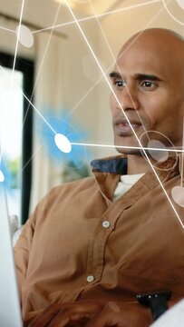 Vertical video: Man checking watch ping, then typing while AR graphs animating over laptop for IT