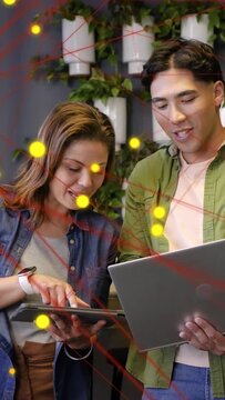 Vertical video: Man with laptop, woman tapping tablet initiating overlay while presenting tech demo