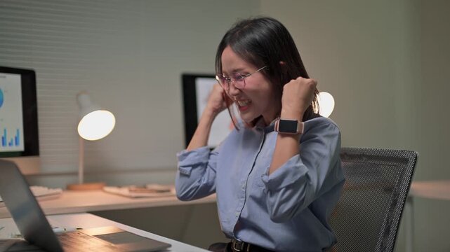 Overjoyed asian businesswoman celebrating success working late at night