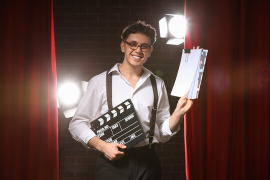 Male screenwriter with scenario and movie clapper on scene