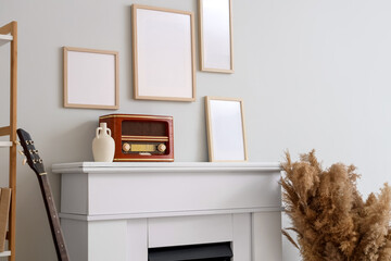 Naklejka premium Interior of stylish room with frames, pampas grass and retro radio on fireplace