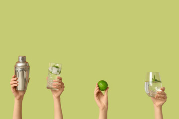 Obraz premium Female hands with glasses of mojito and shaker on green background