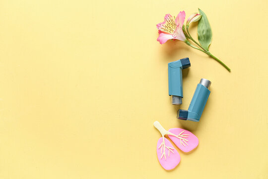 Asthma inhalers with lungs figurine and alstroemeria flower on yellow grunge background