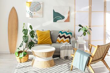 Interior of living room with surfboard, sofa and armchair © Pixel-Shot